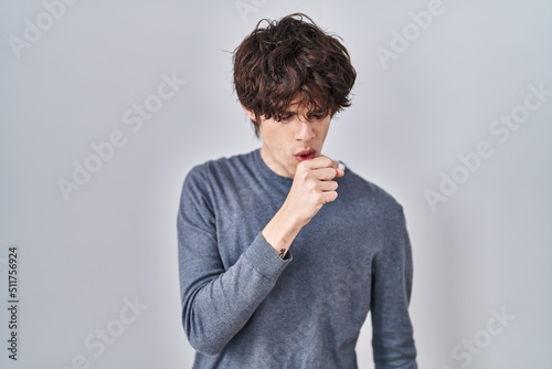 Young man standing over isolated background feeling unwell and coughing as symptom for cold or bronchitis. health care concept. © Krakenimages.com