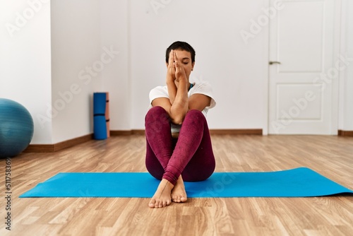 Young hispanic woman training yoga at sport center