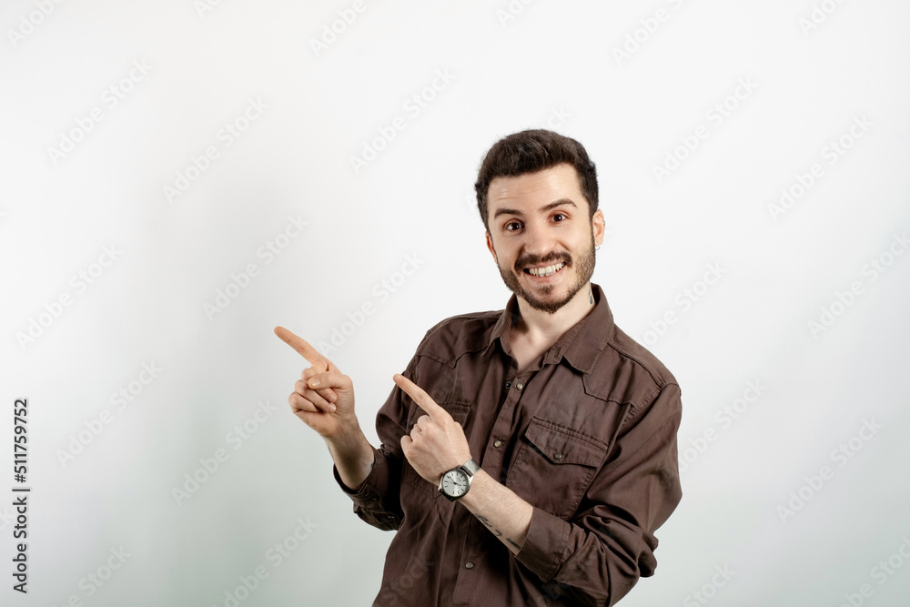 Happy casual man wearing casual clothes posing isolated over white background smiling and looking at the camera pointing with two hands and fingers to the side. Happy casual man wearing casual clothes posing isolated over white background smiling and looking at the camera pointing with two hands and fingers to the side.