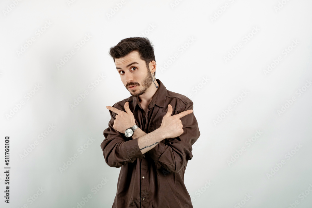 Caucasian man wearing brown shirt posing isolated over white background crossed hands and pointing to copy space on both sides. Caucasian man wearing brown shirt posing isolated over white background crossed hands and pointing to copy space on both sides.