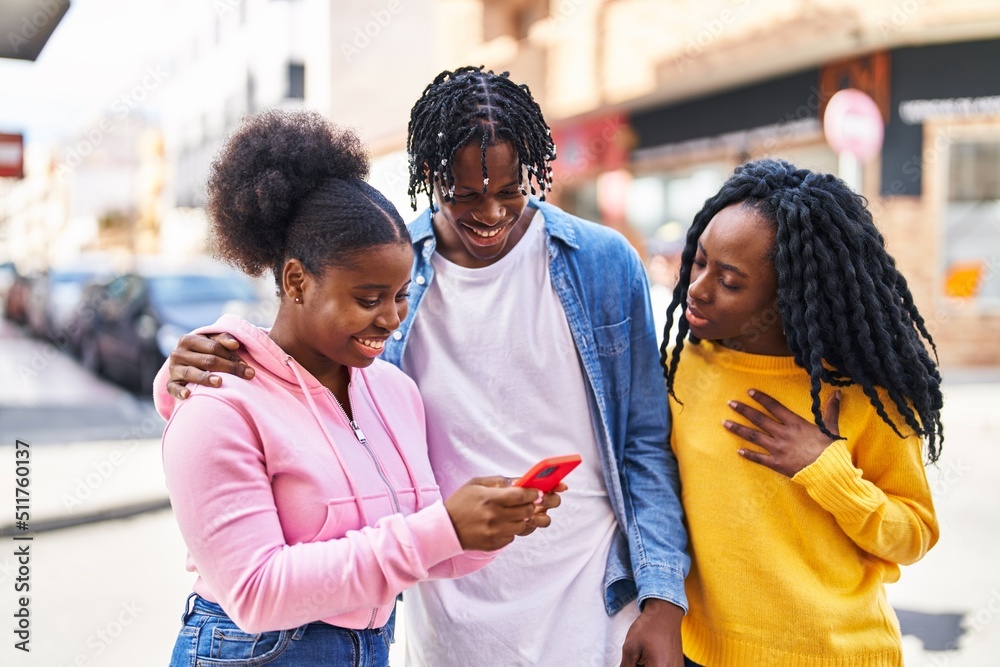 Obraz premium African american friends standing together using smartphone at street