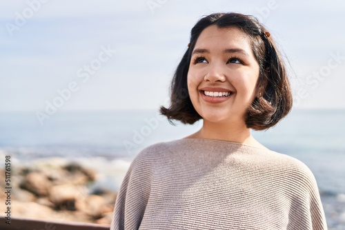 Young woman smiling confident looking to the side at seaside