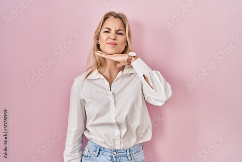 Young caucasian woman wearing casual white shirt over pink background cutting throat with hand as knife, threaten aggression with furious violence