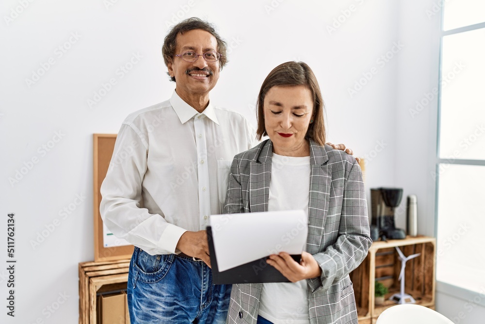Middle age man and woman business workers smiling confident reading document at office Middle age man and woman business workers smiling confident reading document at office