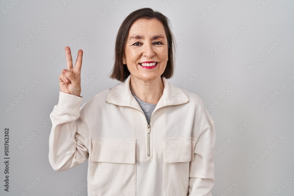 Middle age hispanic woman standing over isolated background showing and pointing up with fingers number two while smiling confident and happy. Middle age hispanic woman standing over isolated background showing and pointing up with fingers number two while smiling confident and happy.