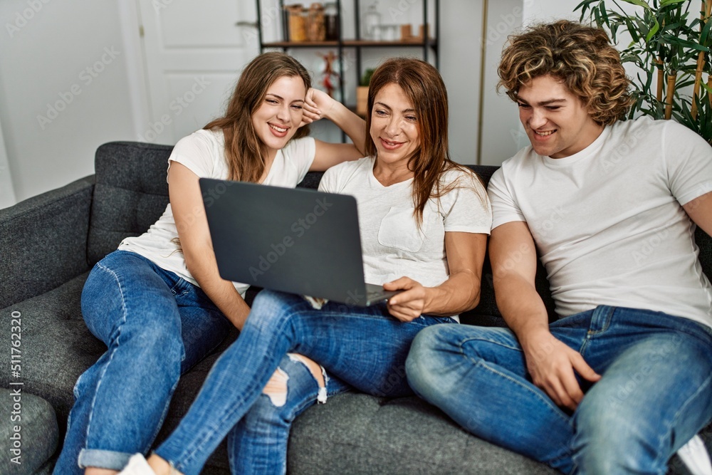 Mother and couple using laptop sitting on sofa at home