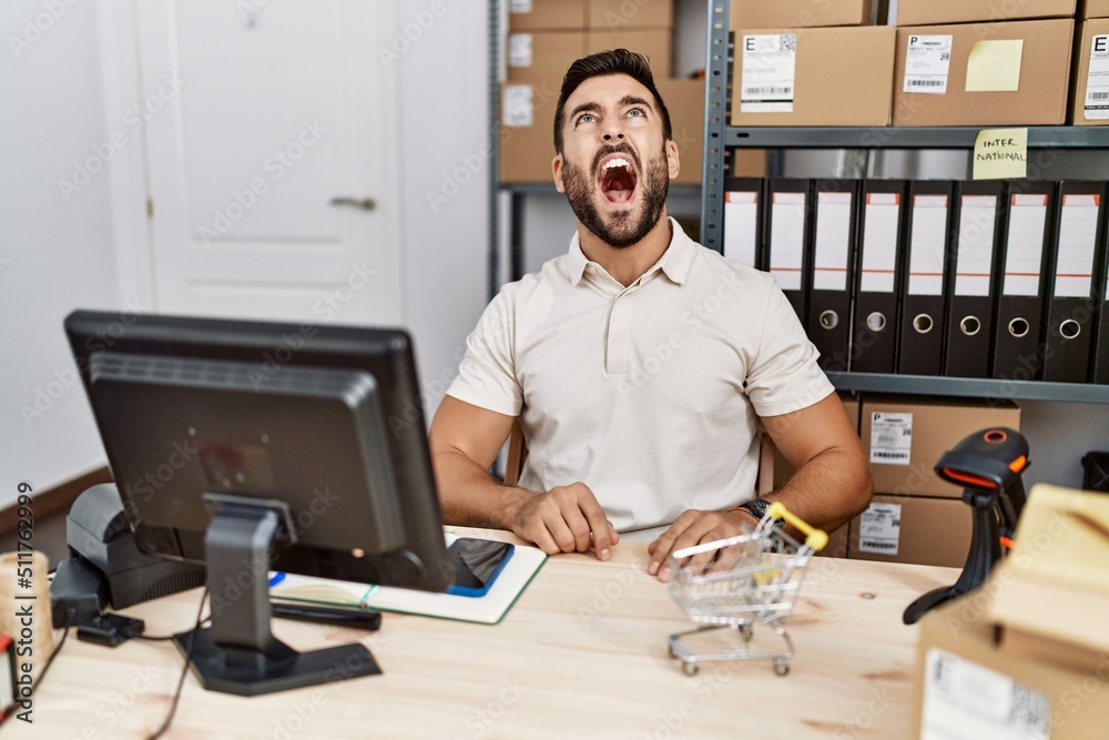 Handsome hispanic man working at small business commerce angry and mad screaming frustrated and furious, shouting with anger. rage and aggressive concept. Handsome hispanic man working at small business commerce angry and mad screaming frustrated and furious, shouting with anger. rage and aggressive concept.