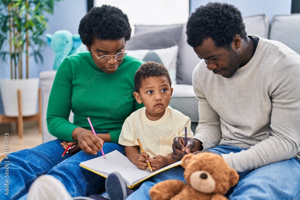 African american family drawing on notebook sitting on floor at home African american family drawing on notebook sitting on floor at home