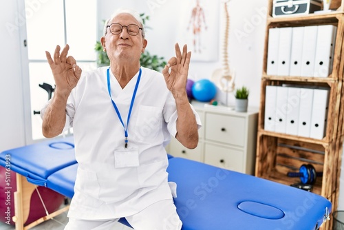 Senior physiotherapy man working at pain recovery clinic relax and smiling with eyes closed doing meditation gesture with fingers. yoga concept.