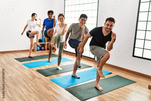 Group of young sporty people smiling happy training yoga at sport center.