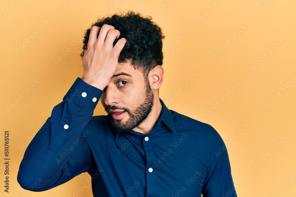 Young arab man with beard wearing casual shirt surprised with hand on head for mistake, remember error. forgot, bad memory concept.
