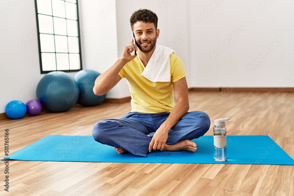 Fototapeta premium Young arab sporty man smiling happy talking on the smartphone at sport center.