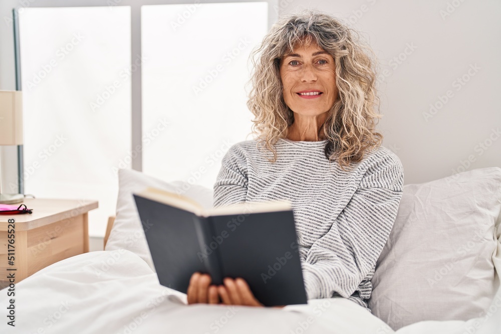 Middle age woman reading book sitting on bed at bedroom Middle age woman reading book sitting on bed at bedroom