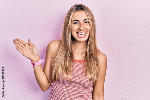 Beautiful hispanic woman wearing casual summer t shirt smiling cheerful presenting and pointing with palm of hand looking at the camera.