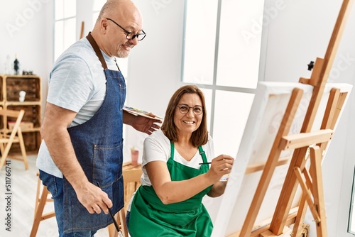 Middle age hispanic painter couple smiling happy painting at art studio.