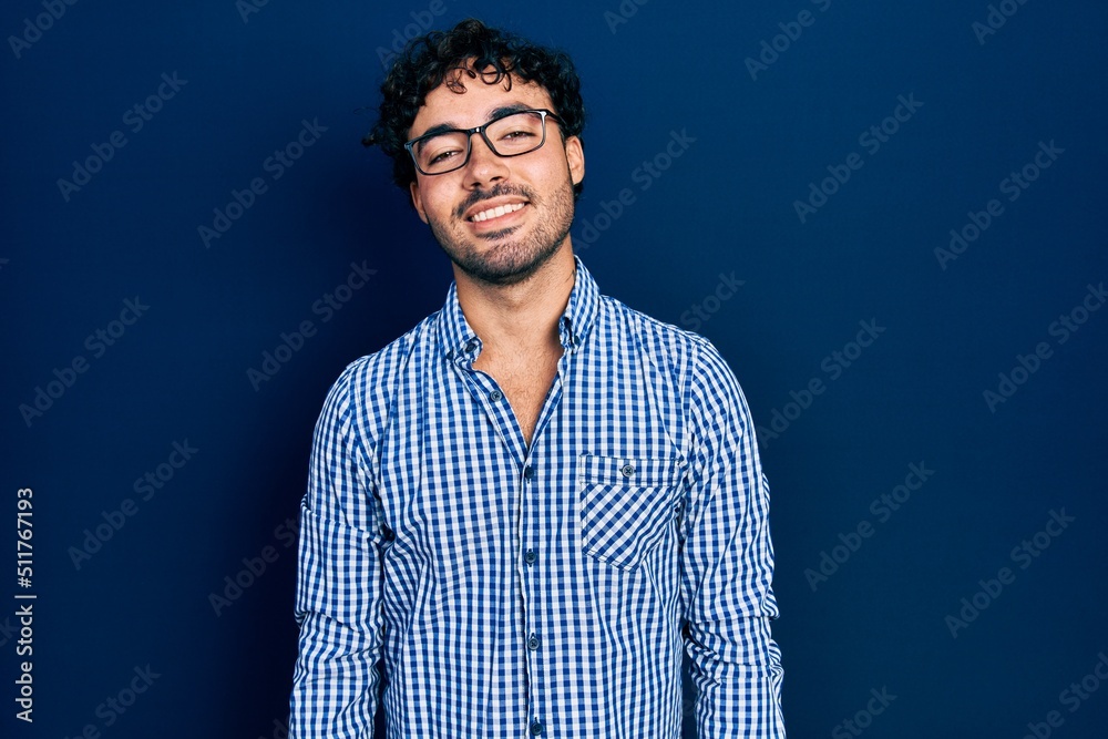 Fototapeta premium Young hispanic man wearing casual clothes and glasses with a happy and cool smile on face. lucky person.