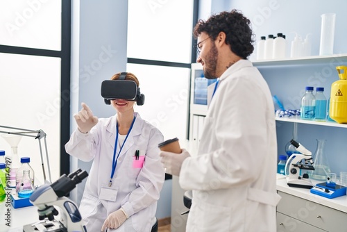 Man and woman scientist partners using vr goggles and drinking coffee at laboratory