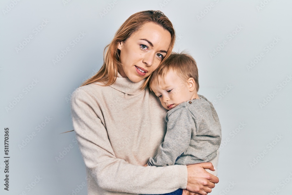 Young caucasian woman holding and hugging her son with love. Family of two bonding together. Mother holding infant toddler