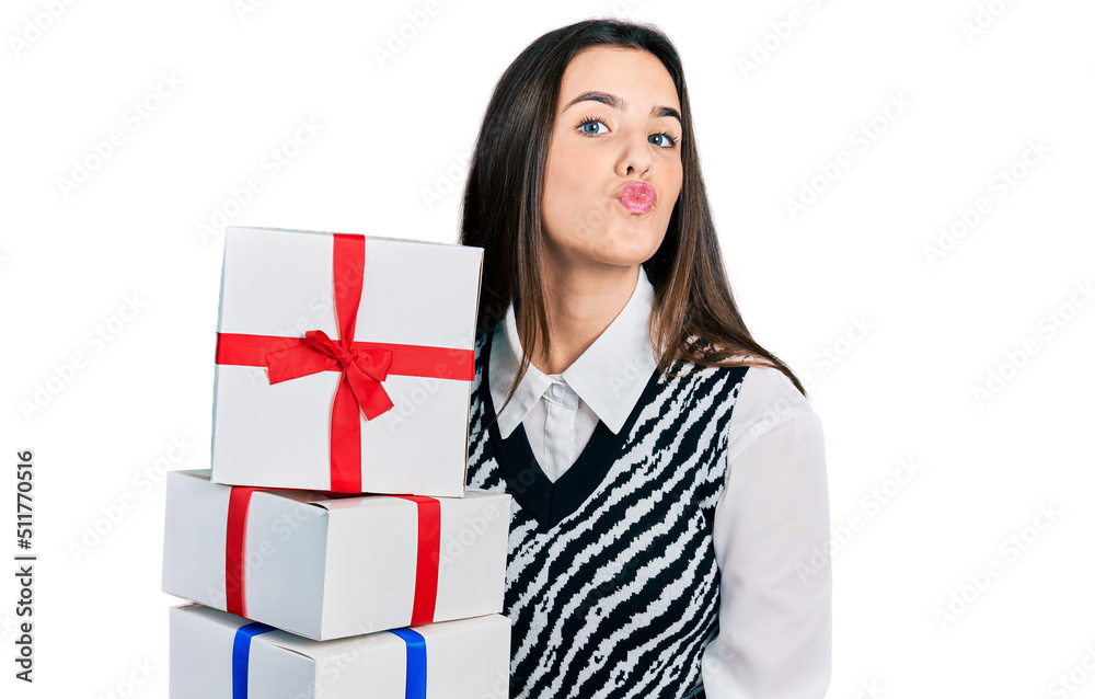 Young brunette teenager holding gifts looking at the camera blowing a kiss being lovely and sexy. love expression. Young brunette teenager holding gifts looking at the camera blowing a kiss being lovely and sexy. love expression.