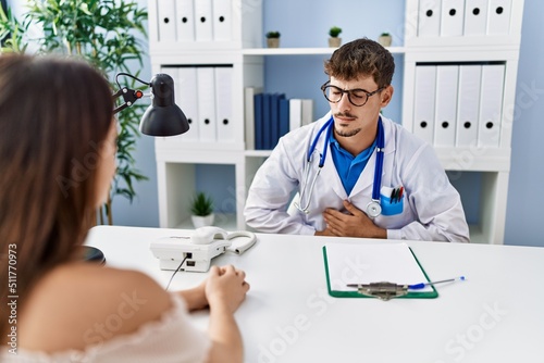 Fototapeta Naklejka Na Ścianę i Meble -  Young doctor with client at medical clinic with hand on stomach because indigestion, painful illness feeling unwell. ache concept.