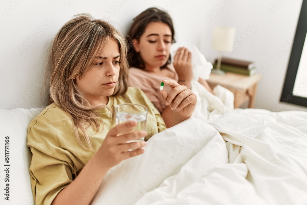 Young ill couple using napkin and eating pills lying on the bed at home.