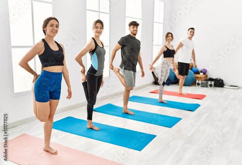 Group of young hispanic people smiling happy training yoga at sport center.