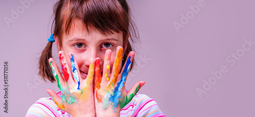 Portrait of happy little cute child girl with colorful painted hands as symbol of happiness and joyful life. Copy space.
