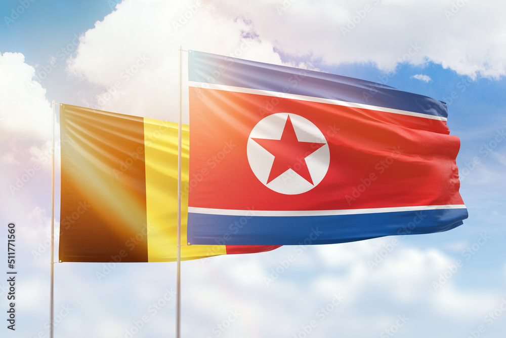 Sunny blue sky and flags of north korea and belgium Sunny blue sky and flags of north korea and belgium