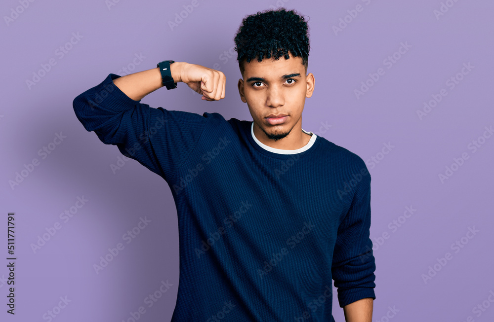 Young african american man wearing casual clothes strong person showing arm muscle, confident and proud of power Young african american man wearing casual clothes strong person showing arm muscle, confident and proud of power