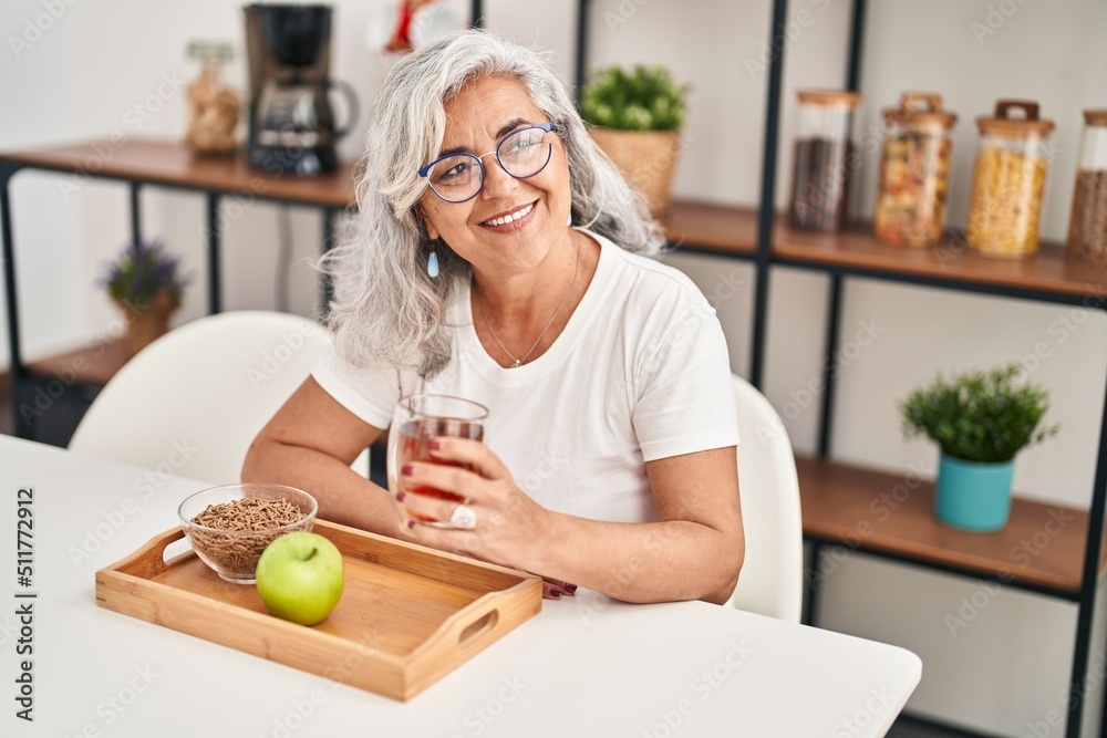 Middle age woman smiling confident having breakfast at home