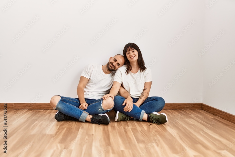 Young hispanic couple smiling happy sitting on the floor at empty new home. Young hispanic couple smiling happy sitting on the floor at empty new home.
