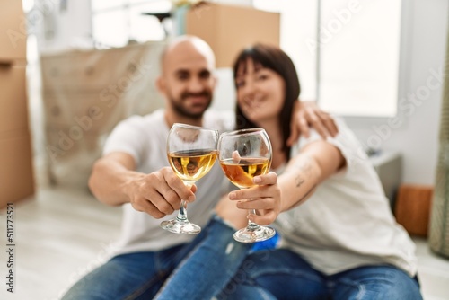 Young hispanic couple smiling happy toasting with champagne at new home.