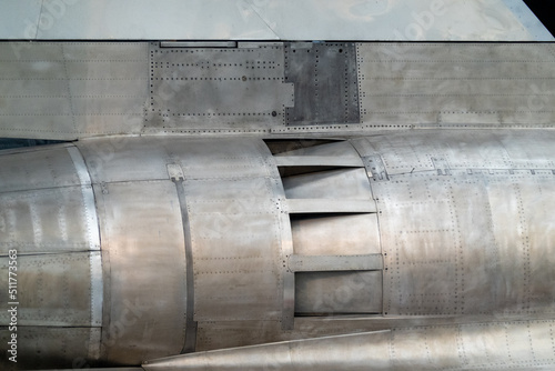 Detail of aircraft jet engine, near exhaust, with matte-finish metal panels, riveted in place. Suitable for background for graphics and text