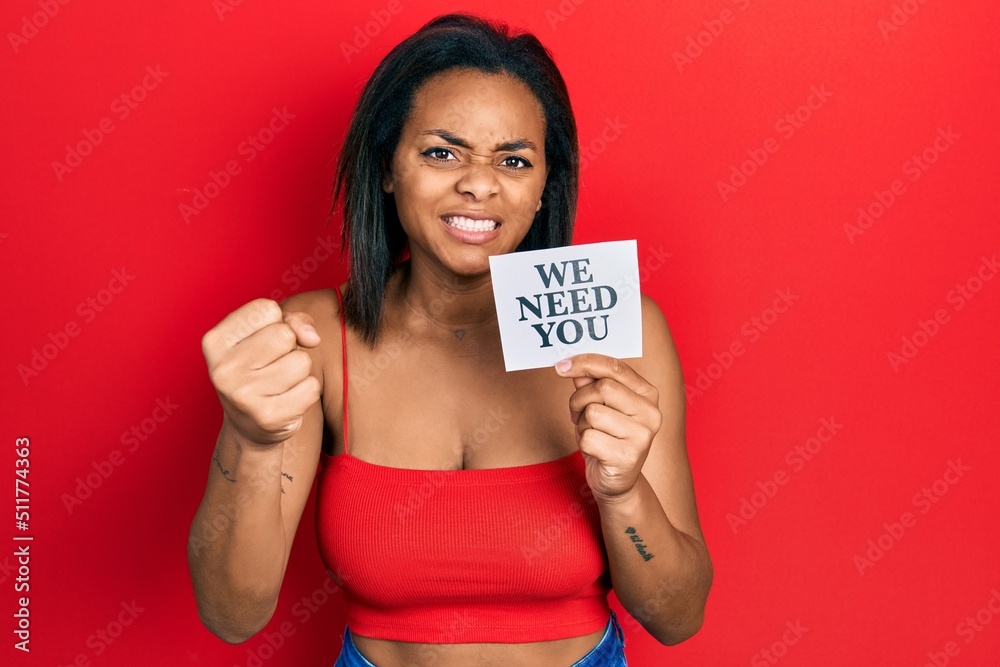 Young african american girl holding we need you paper annoyed and frustrated shouting with anger, yelling crazy with anger and hand raised Young african american girl holding we need you paper annoyed and frustrated shouting with anger, yelling crazy with anger and hand raised