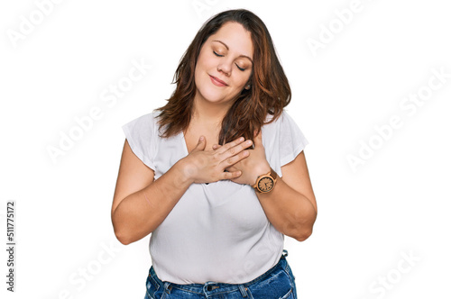 Young plus size woman wearing casual white t shirt smiling with hands on chest with closed eyes and grateful gesture on face. health concept.