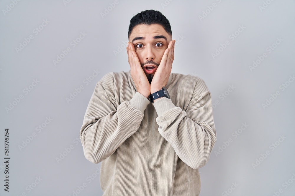 Young handsome man standing over isolated background afraid and shocked, surprise and amazed expression with hands on face Young handsome man standing over isolated background afraid and shocked, surprise and amazed expression with hands on face
