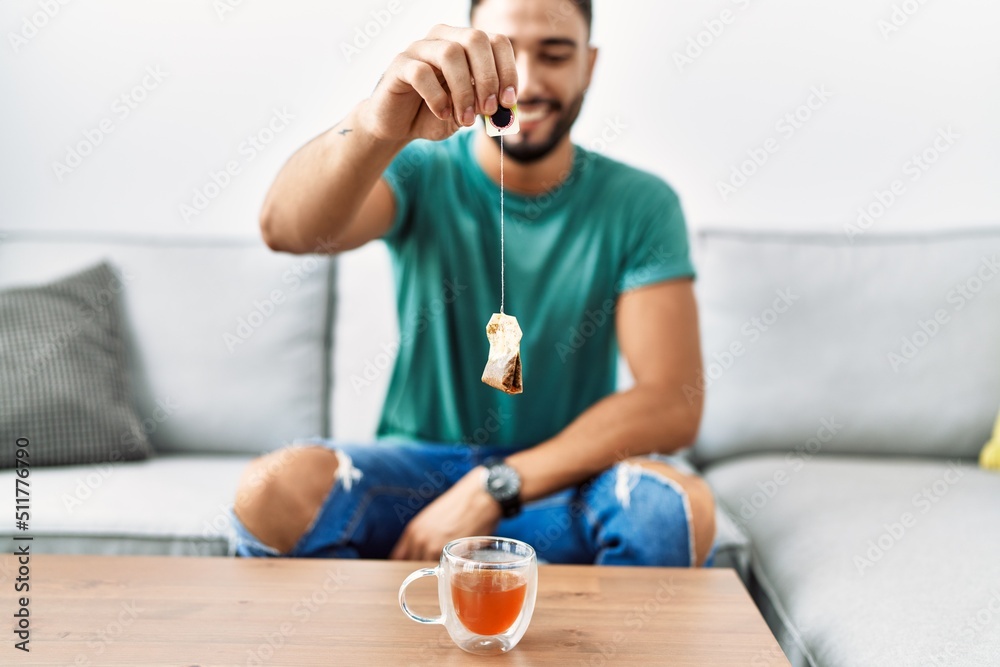 Young arab man smiling confident holding tea bag at home Young arab man smiling confident holding tea bag at home