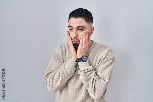 Young handsome man standing over isolated background tired hands covering face, depression and sadness, upset and irritated for problem