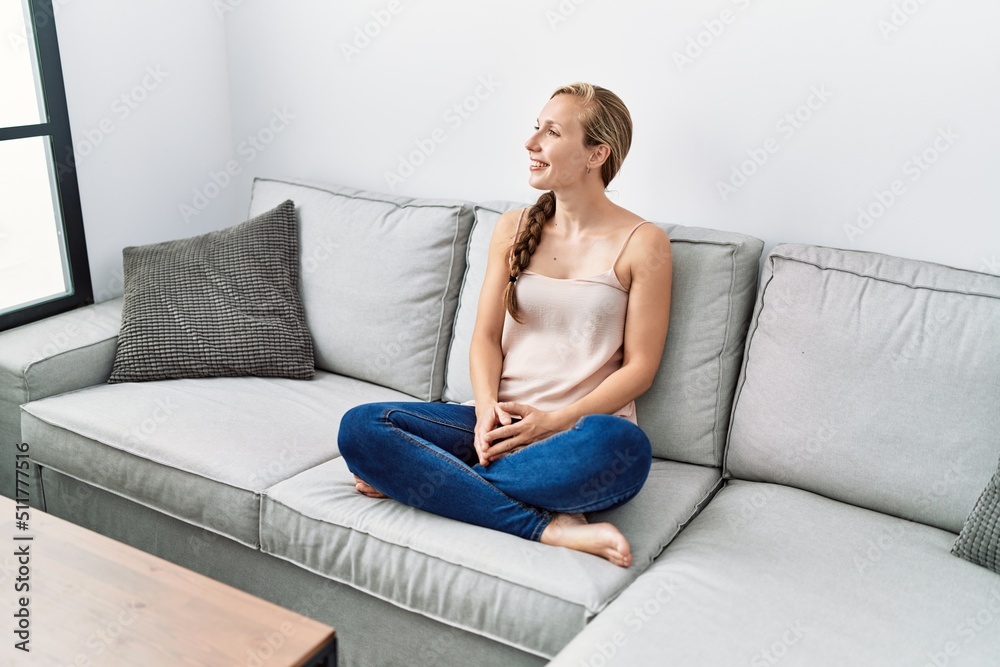Obraz premium Young caucasian woman smiling confident sitting on sofa at home
