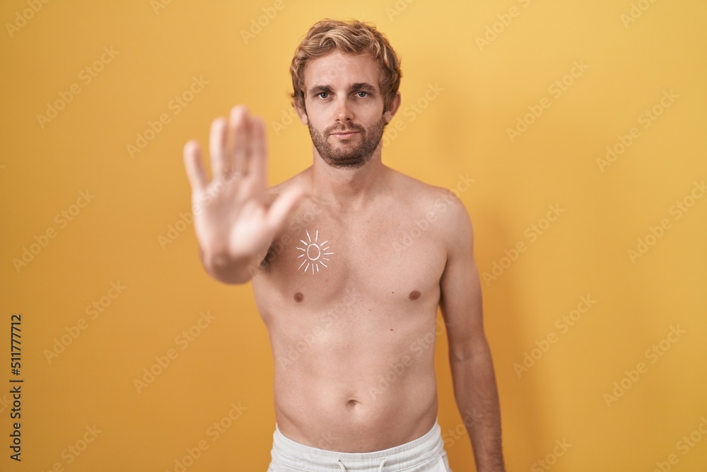 Caucasian man standing shirtless wearing sun screen doing stop sing with palm of the hand. warning expression with negative and serious gesture on the face.