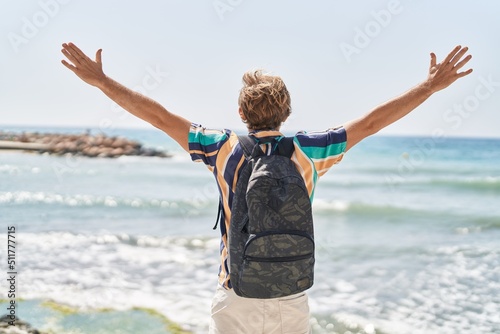 Fotomurale Young man tourist wearing backpack with arms open at seaside