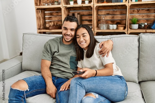 Young latin couple smiling happy watching tv at home.