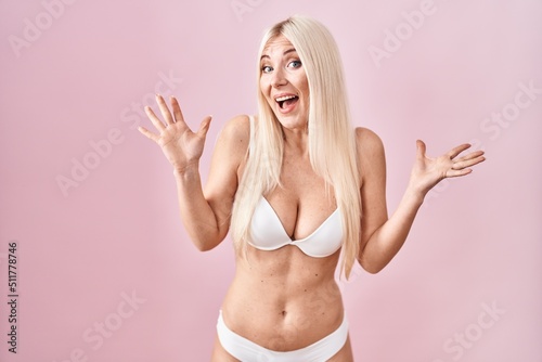 Caucasian woman wearing lingerie over pink background celebrating crazy and amazed for success with arms raised and open eyes screaming excited. winner concept