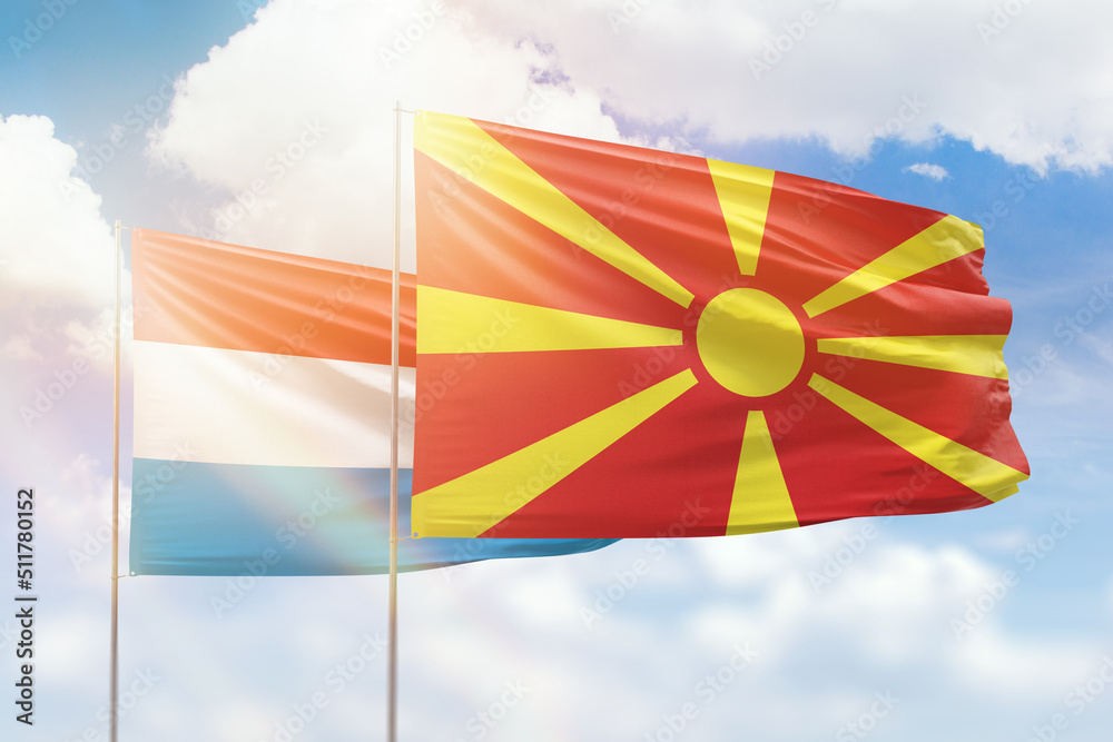 Sunny blue sky and flags of north macedonia and luxembourg
