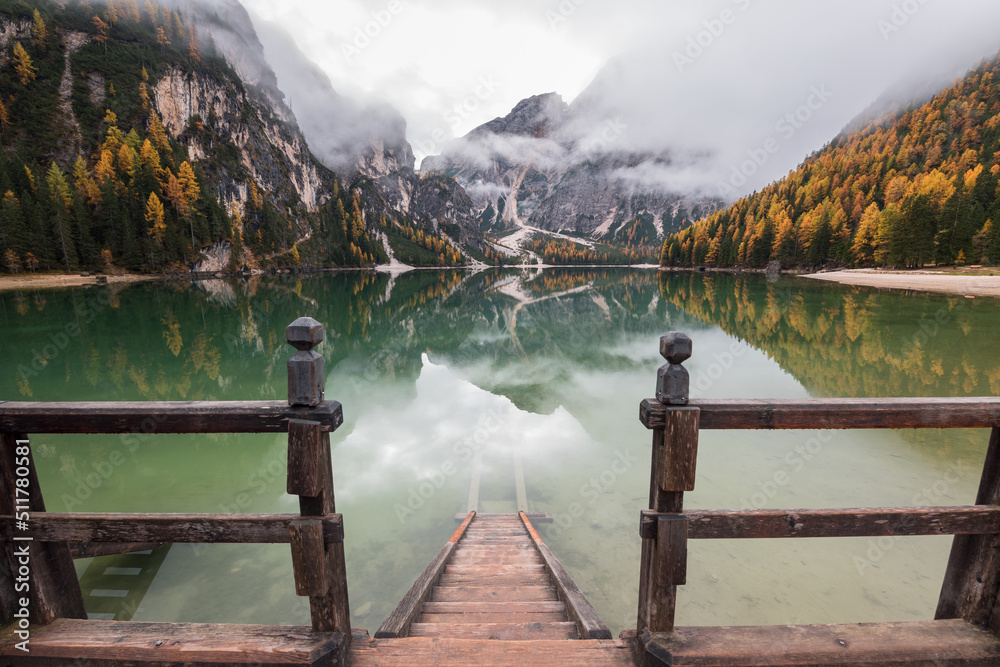 Beautiful autumn day by lake Braies in the Dolomites on a moody morning. Fog and clouds rolling over the mountains.