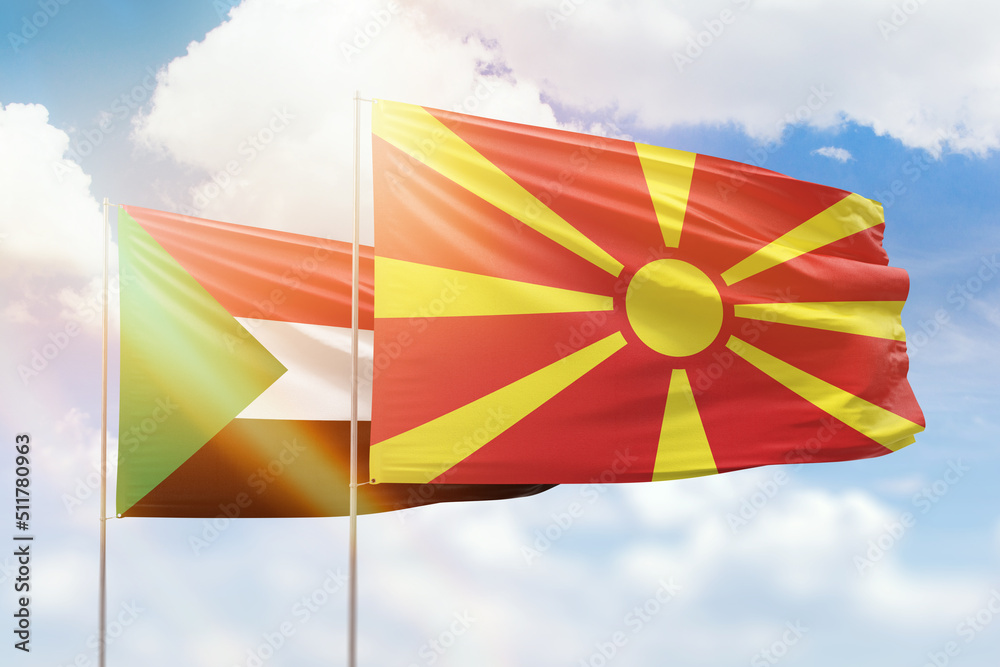 Sunny blue sky and flags of north macedonia and sudan