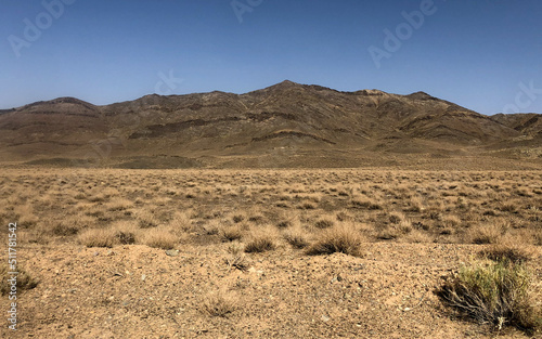Scenic View Of Mountains Against Clear Blue Sky And Dry Desert Land With Many Small Bushes and Dried Plants In Isfahan Iran
