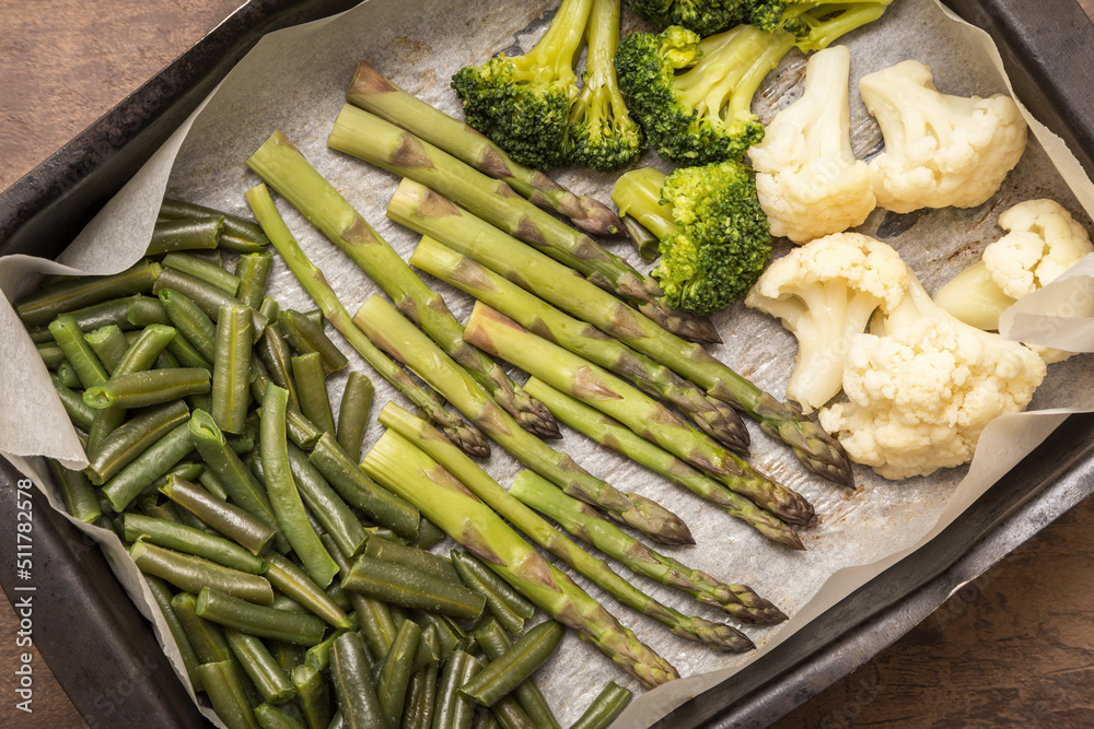 Baked vegetables asparagus, broccoli and cauliflower on parchment paper close-up. Vegan healthy diet food concept