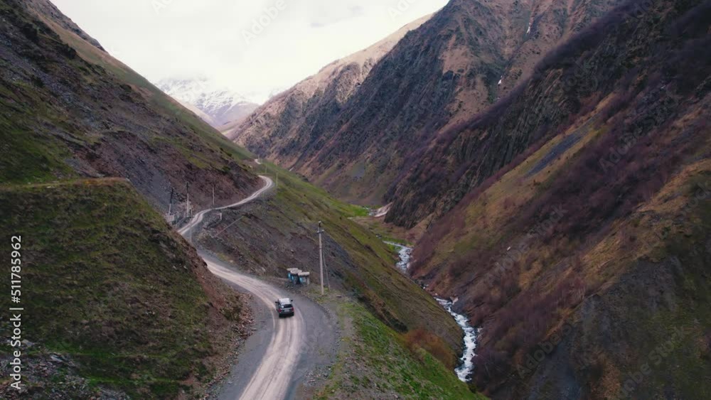 Winding off-road track in the mountains and a car driving through it. Aerial drone view. High quality 4k footage Winding off-road track in the mountains and a car driving through it. Aerial drone view. High quality 4k footage