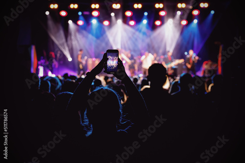 Holding a smartphone to record music concert. Mobile phone at a summer festival.